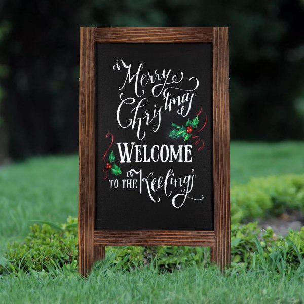 Wooden chalkboard sign with holiday message and holly decorations.
