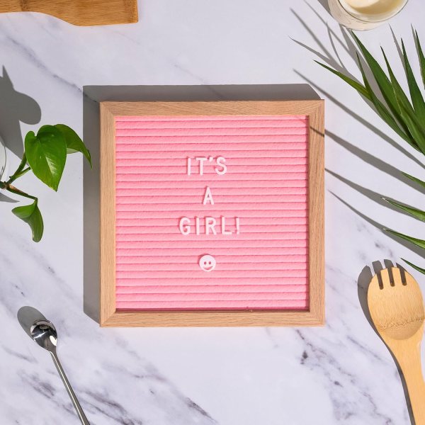 Pink felt letter board displaying "IT'S A GIRL!" message with smiley face.