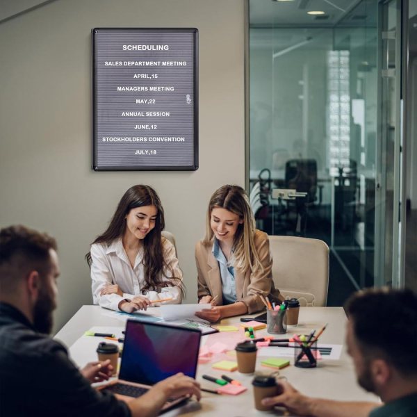 Business team in meeting room with scheduling digital sign on wall.