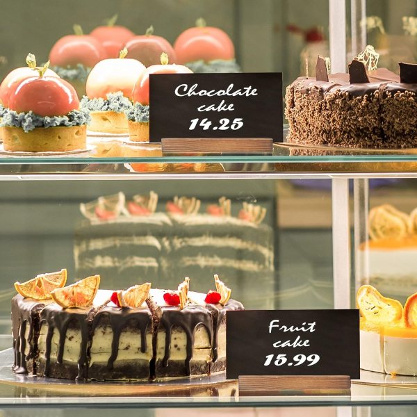 Delicious assorted cakes with fruit and chocolate toppings in bakery display case.